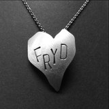 Stort hjartesmykke med diverse tekstar